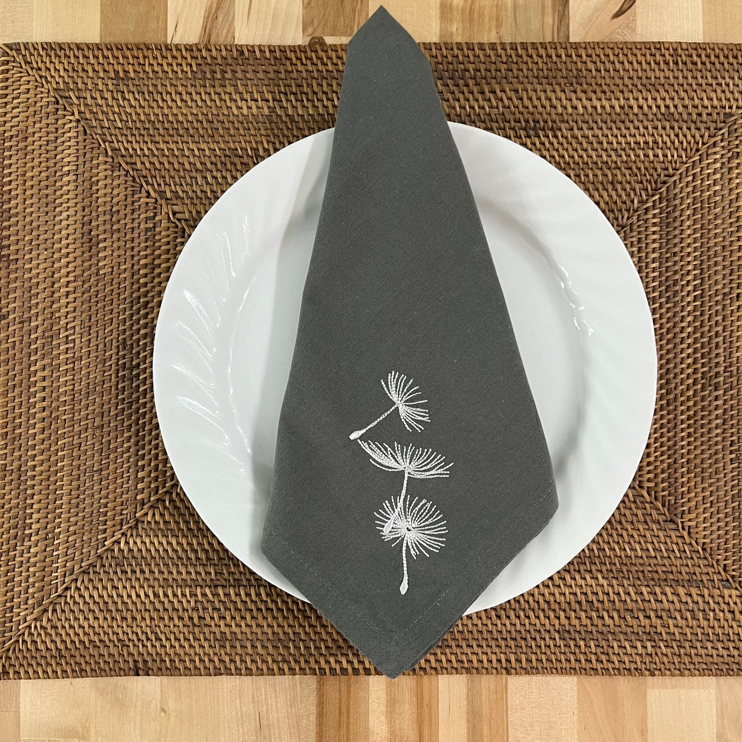 Blowing dandelion embroidered on grey napkin