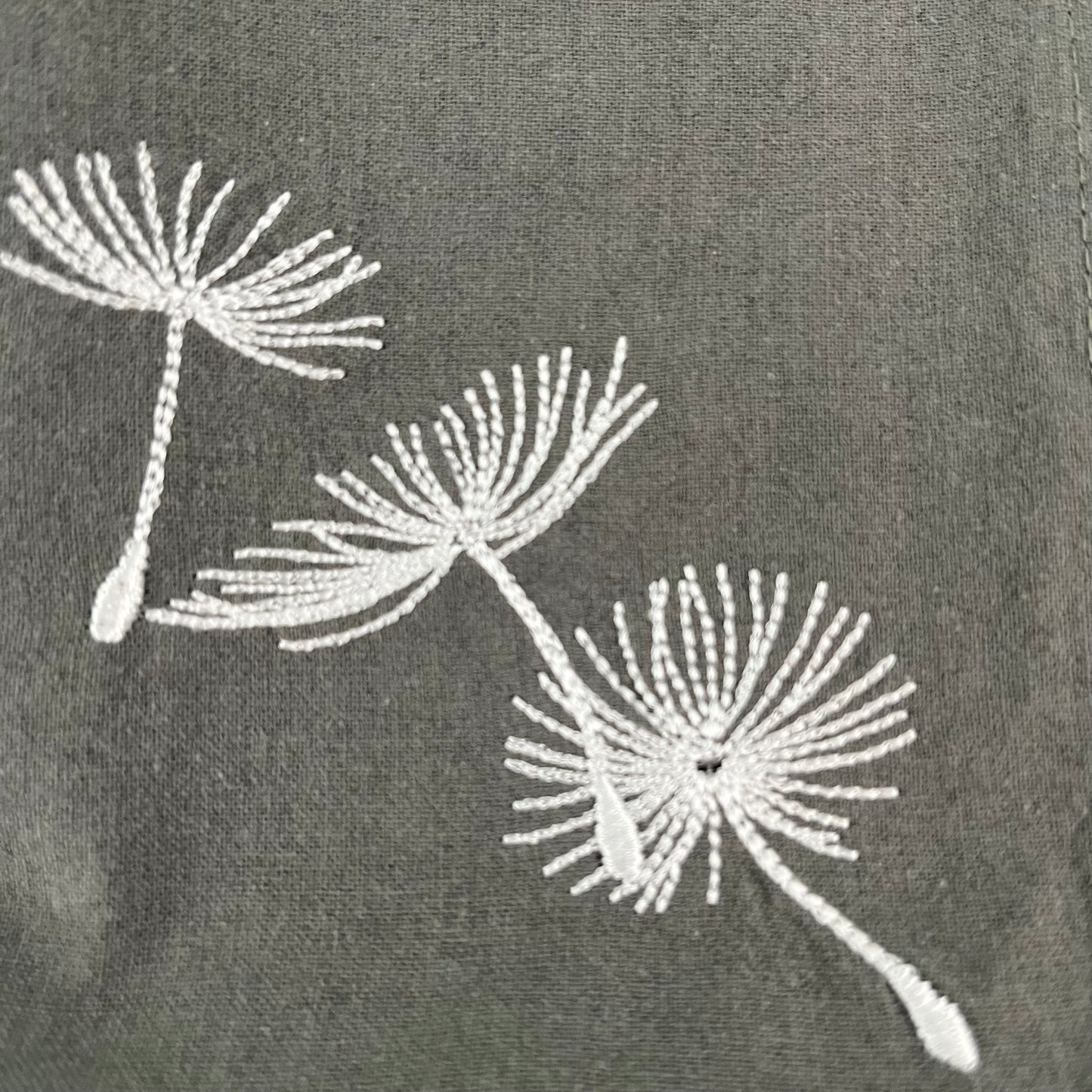 Blowing dandelion embroidered on grey napkin