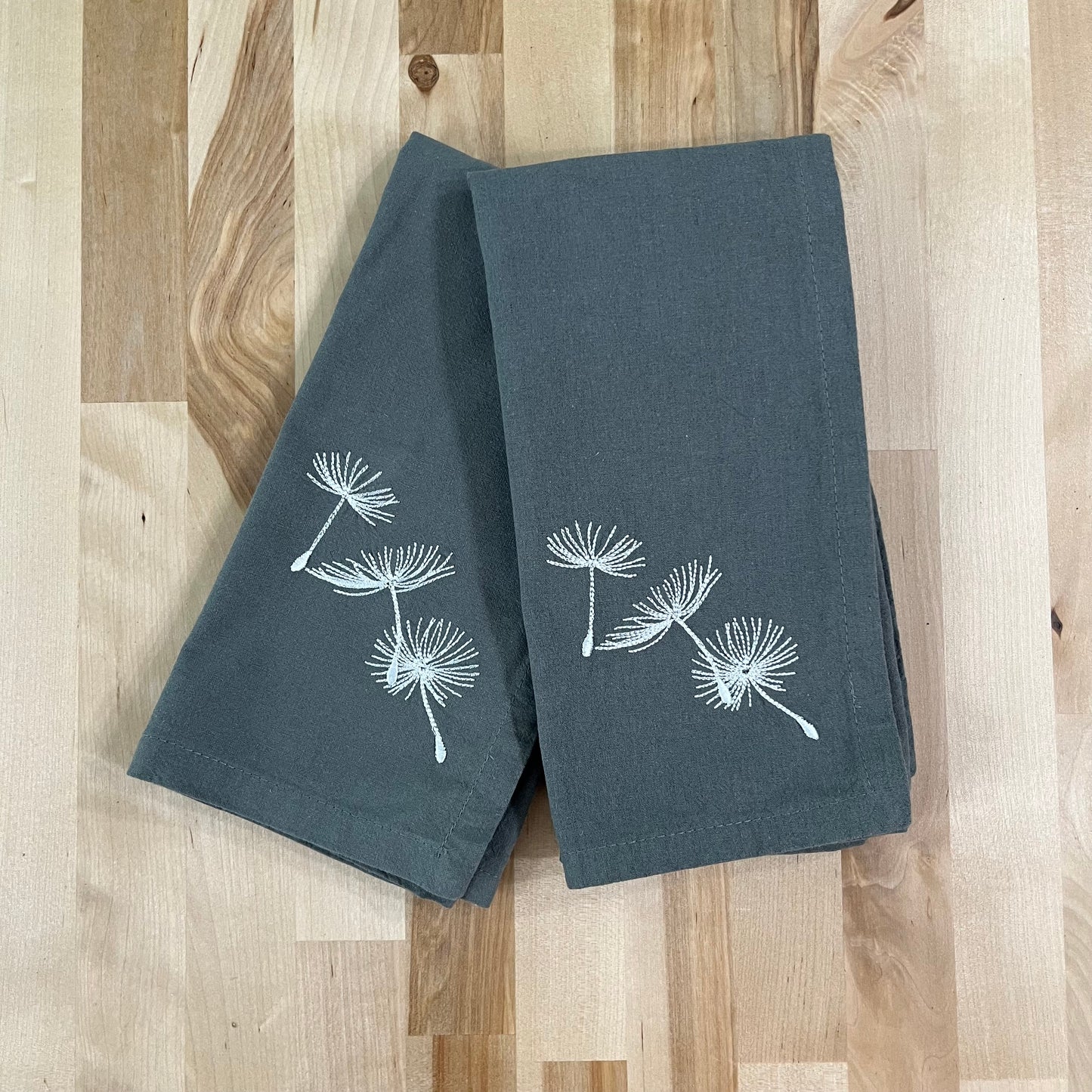 Blowing dandelion embroidered on grey napkin